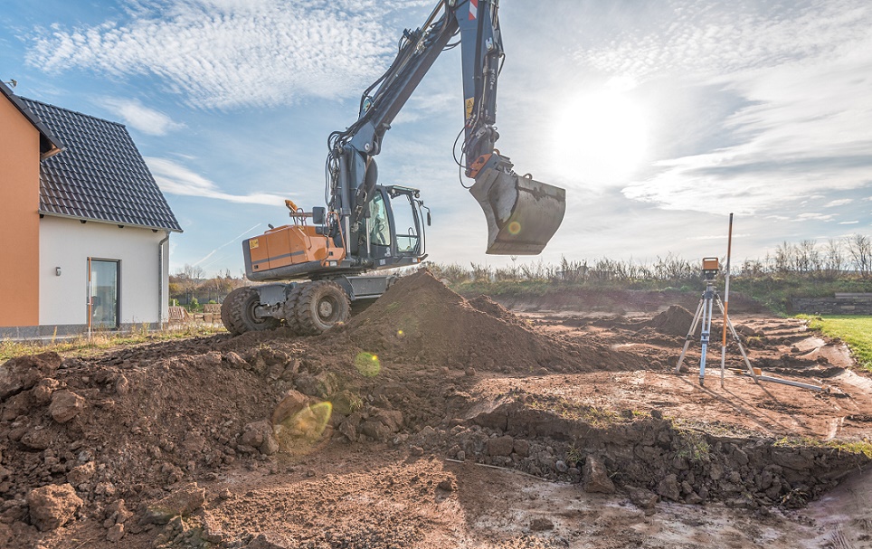 Digger excavating the ground next to new house